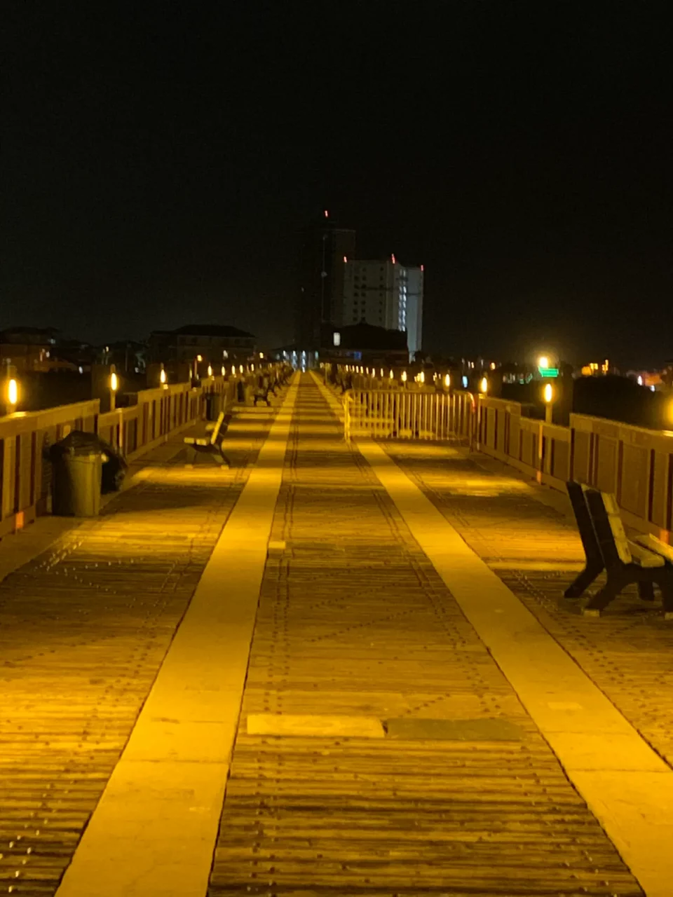 Pier walkway lit with warm deck lighting at night, Casino Beach, Pensacola Beach