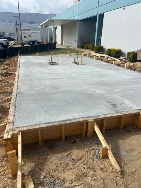 Freshly poured concrete equipment pad inside timber forms