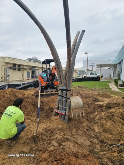Conduit sweeps rising from an excavation beside an excavator