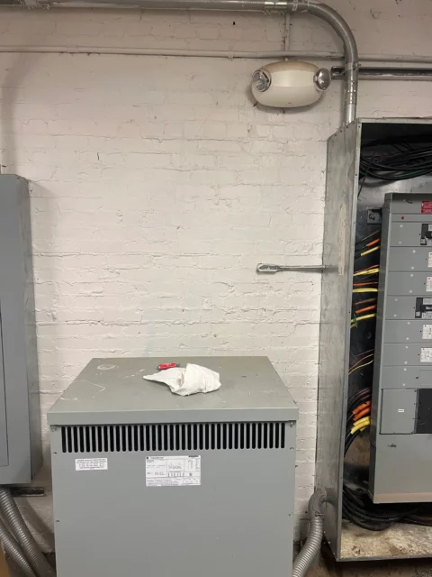 Dry-type transformer and panels in a basement electrical room