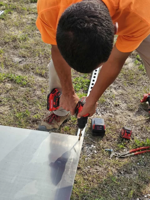 Electrician drilling a mounting plate for an EV charger installation