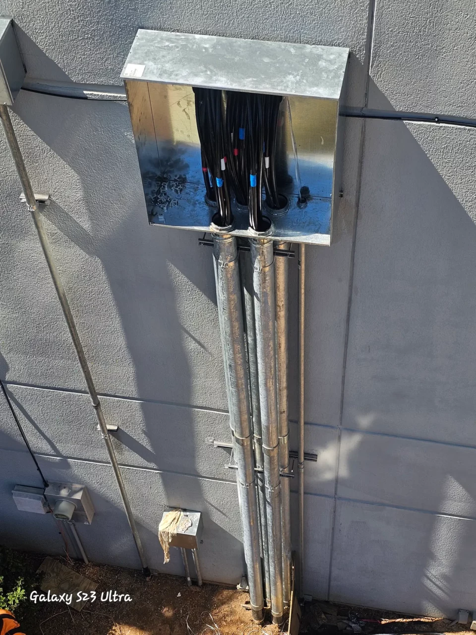 Stainless junction box with conduit risers on a building exterior