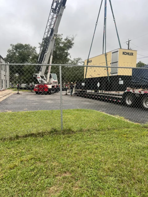 Crane truck setting a Kohler generator inside a fenced equipment yard