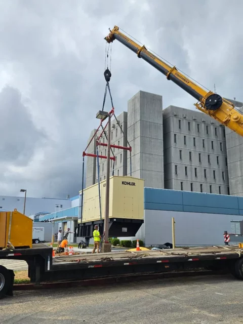Standby generator rigged to a crane on a flatbed trailer before the lift