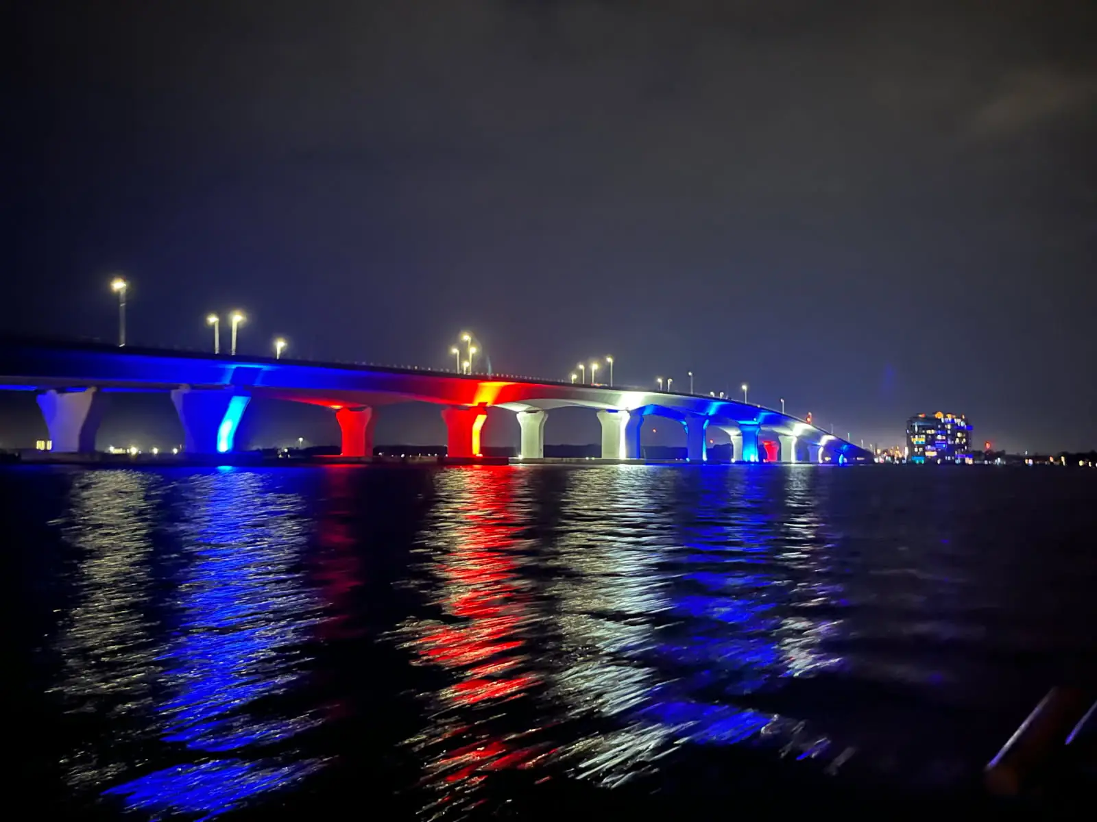 Hathaway Bridge lit red, white and blue for America 250, reflected on the bay at night