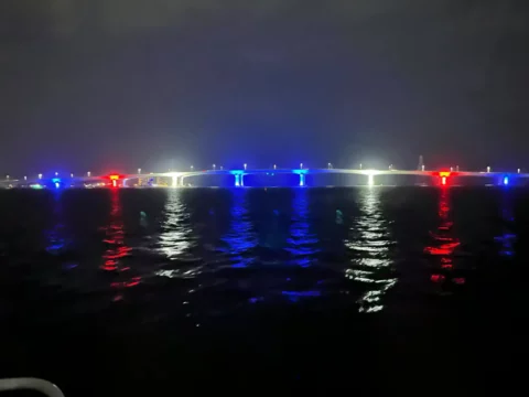 Red, white and blue architectural lighting running the length of the Hathaway Bridge at night