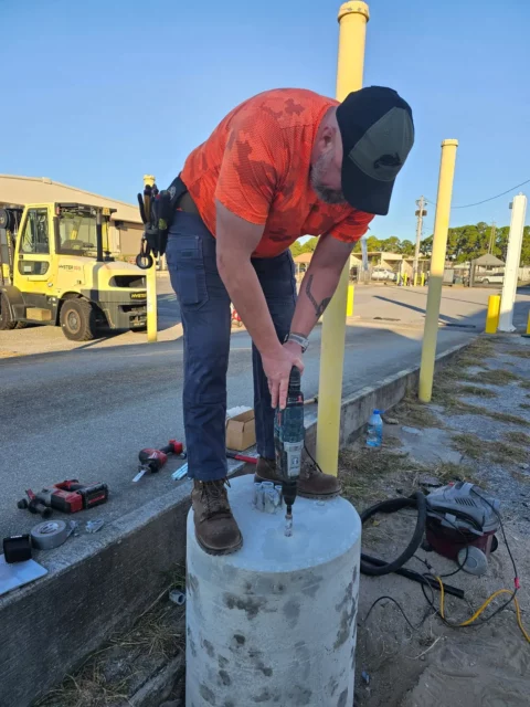 Electrician drilling a concrete light pole base for anchor bolts