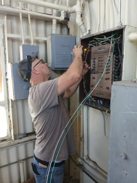 Electrician terminating conductors in an open control panel