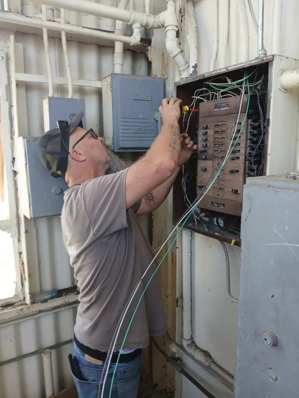 Electrician terminating conductors in an open control panel