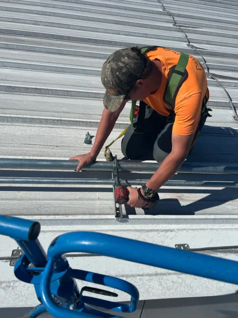 Electrician strapping conduit to a standing-seam metal roof