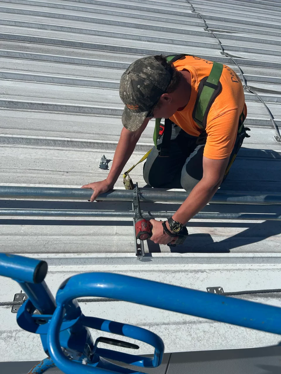 Electrician strapping conduit to a standing-seam metal roof