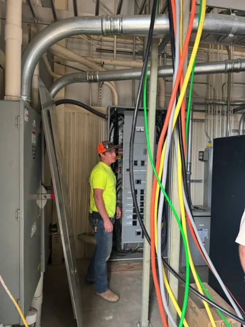 Electrician pulling colour-coded conductors into a panelboard