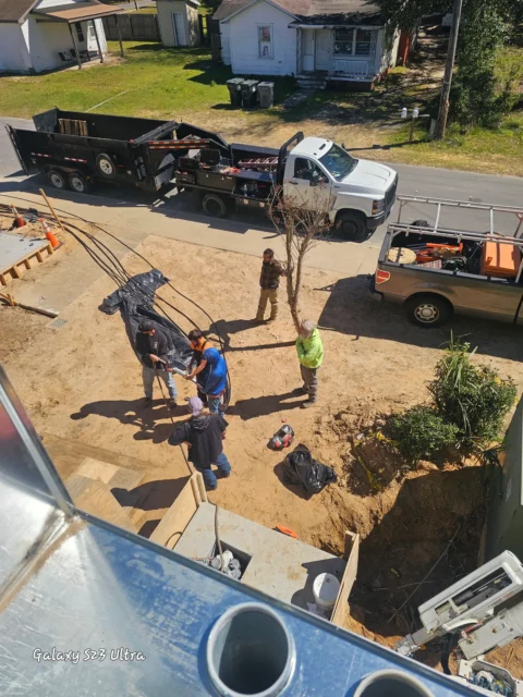 Crew and trucks at an open utility trench, seen from above